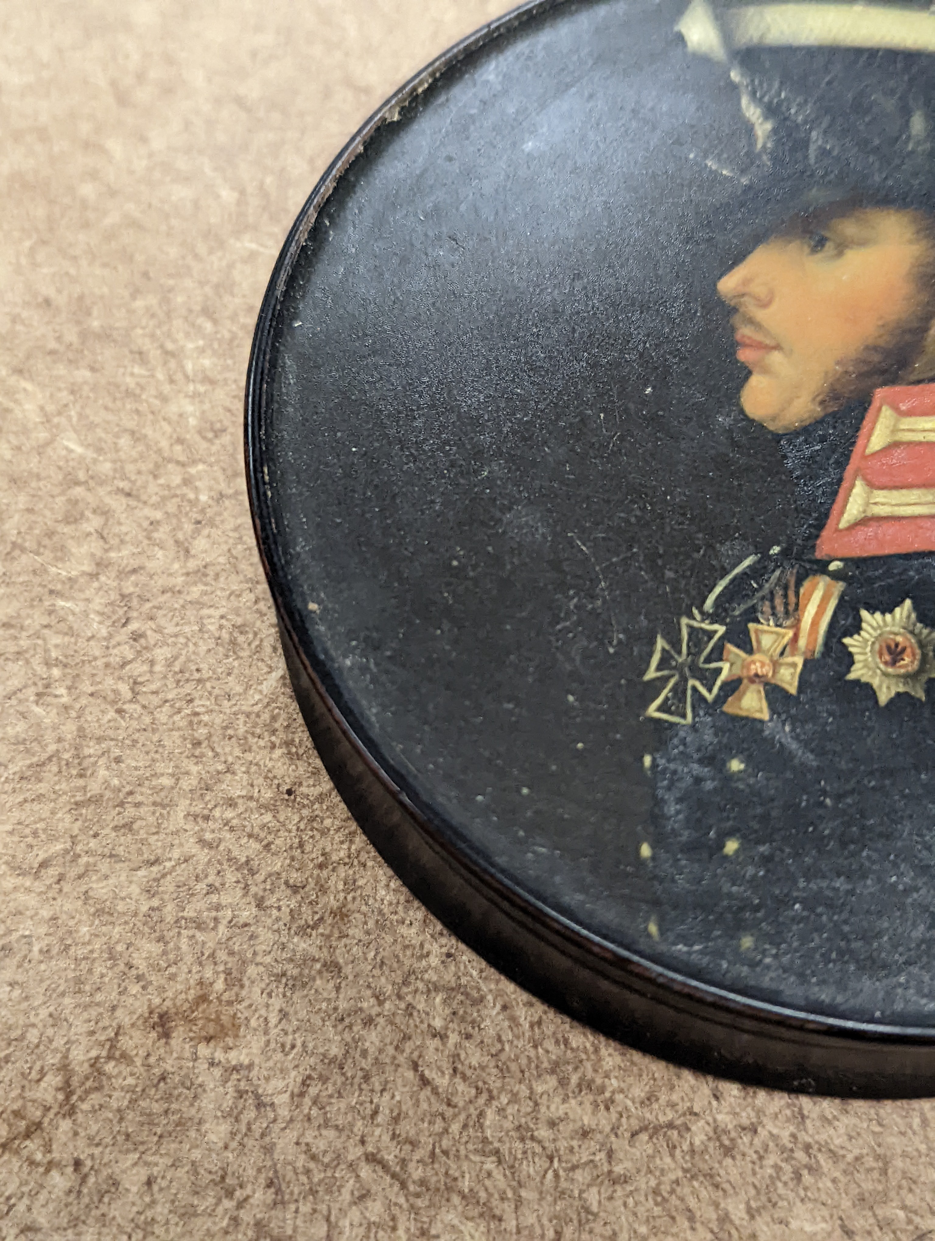 A 19th century Stobwasser papier mache ‘Henriette Sonntag’ portrait snuff box, c.1830, 9.7cm diameter and a 19th-century papier mache snuff box painted with a portrait of a German hussar, 9.4cm (2)